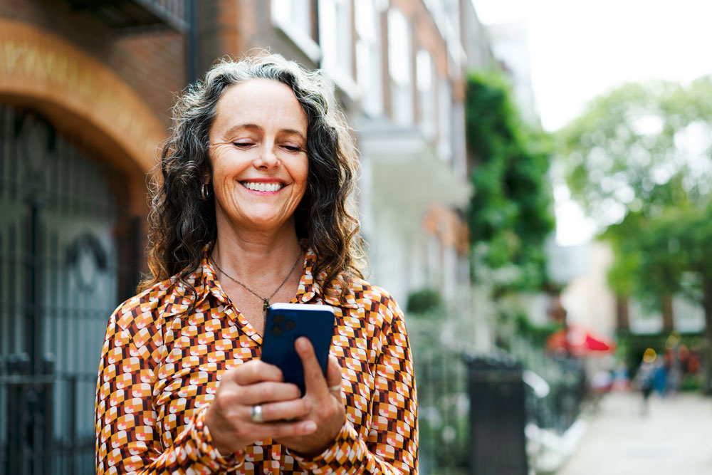 En kvinna ler mot sin mobil